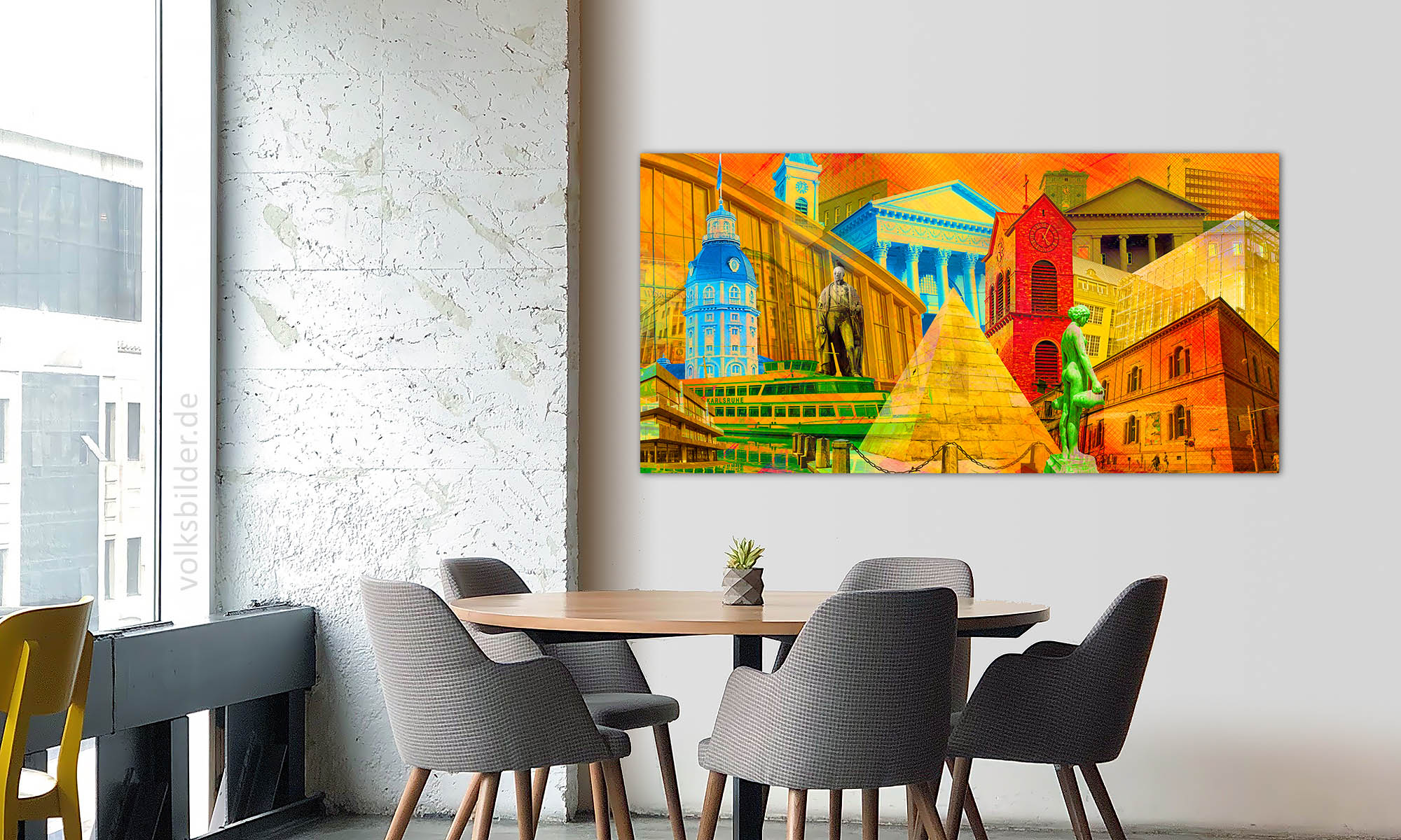 Ein Besprechnungsraum. Im Vordergrund ein runder Tisch mit sesselartigen Stühlen. An der Wand im Hintergrund hängt ein grafisches Wandbild im Pop Art Stil, das viele bunt eingefärbte Karlsruher Gebäude zeigt.