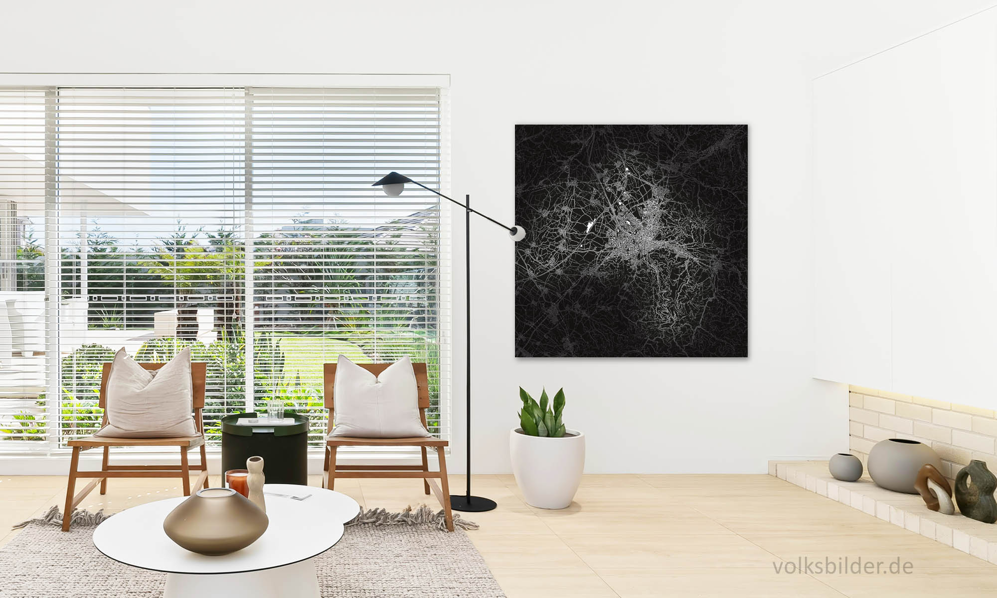 Ein Foto, das ein Wohnzimmer zeigt. Im linken Teil des Bildes stehen zwei stuhlähnliche Sessel vor einem großen Fenster. Daneben hängt an einer Wand eine stilisierte Landkarte von Freiburg und Umgebung. Diese ist schwarzweiß und stellt Straßen, Gewässer und Gebäude weiß vor schwarzem Hintergrund dar. 