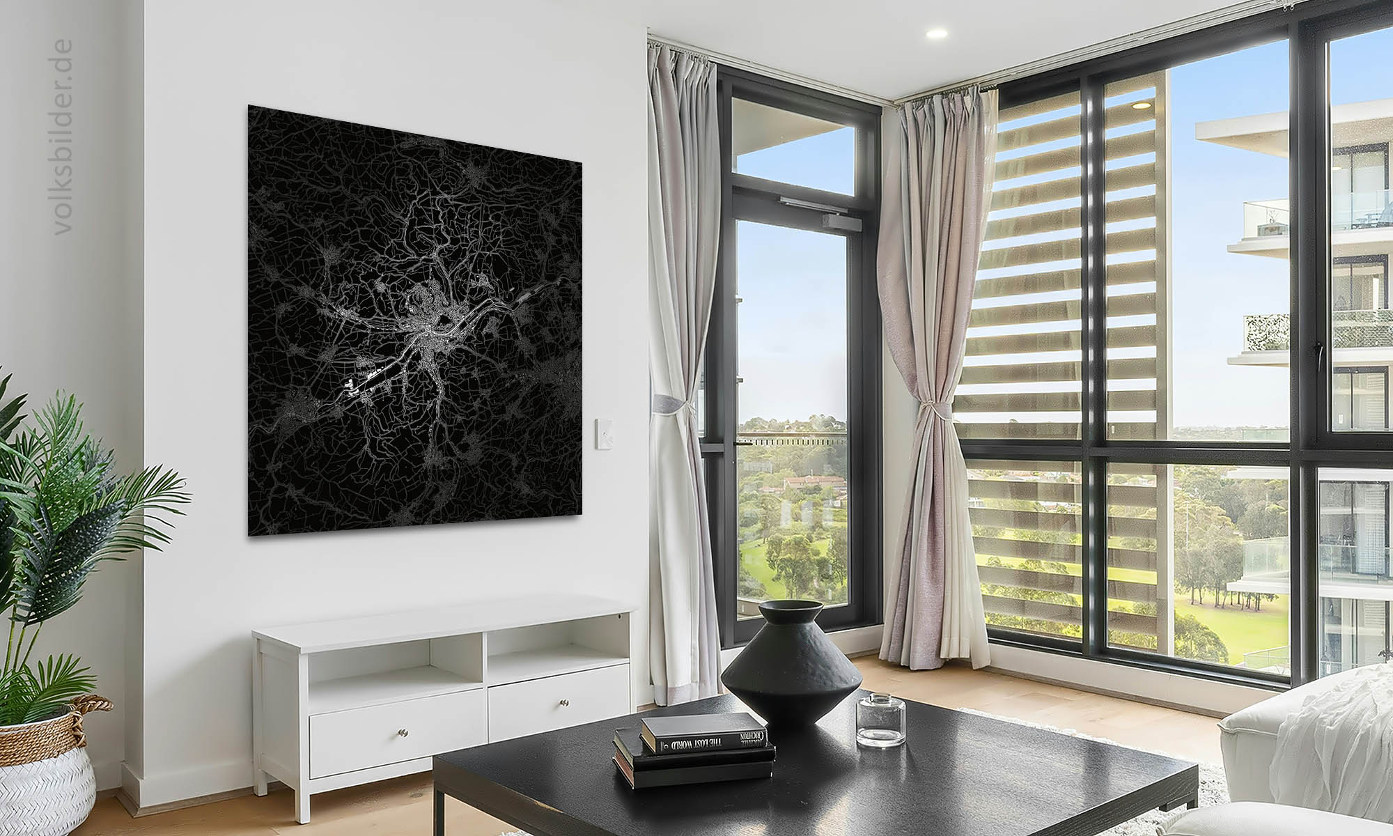 Foto eines Wohnzimmers in einem Hochhaus. Links an der Wand im Hintergrund hängt ein Wandbild mit einer stilisierten Karte in Schwarzweiß von Tübingen und Umgebung. Rechts seiht ma durch ein großes Fenster ein weiteres Hochhaus.